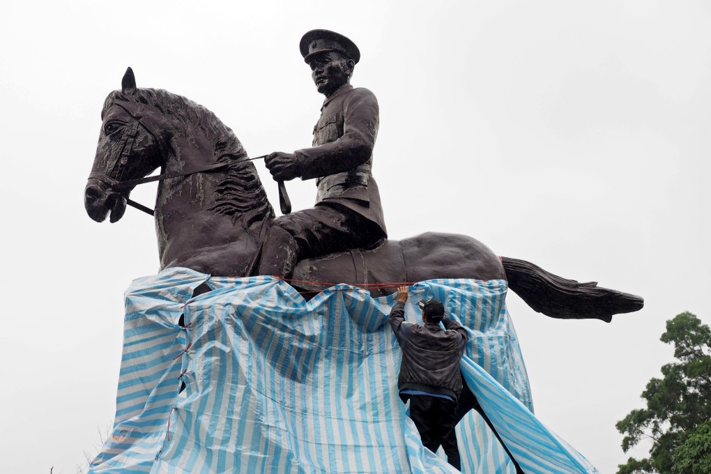 A man covers up the vandalised statue of Chiang Kai-shek in Taipei. Photo: EPA-EFE