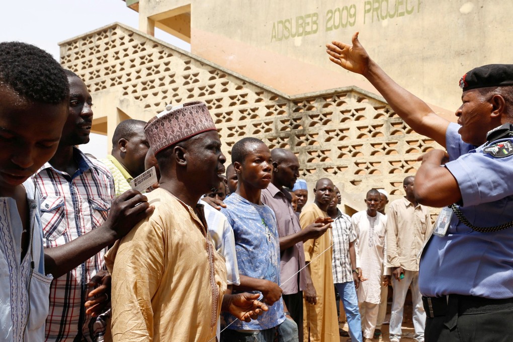 A security guard gestures as people gather to cast their vote during Nigeria's presidential election at Capital School polling unit, in Yola, Adamawa State. Photo: Reuters