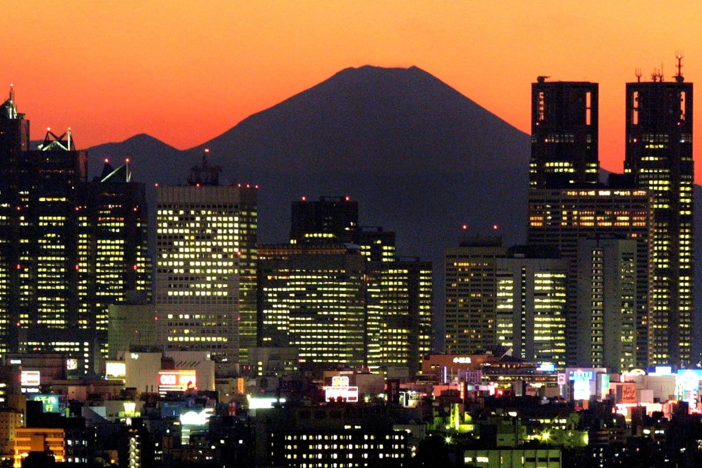 Japan’s highest mountain, Mt Fuji, is seen in the background between skyscrapers in Tokyo. Japan is looking to draw 40 million tourists a year. Photo: AFP