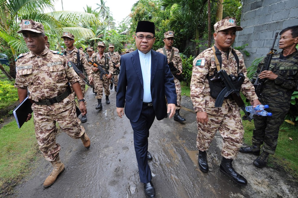 Murad Ebrahim, chairman of the Moro Islamic Liberation Front, being escorted by his troops to a press conference inside their base at Camp Darapan, on the Philippine island of Mindanao. Photo: AFP