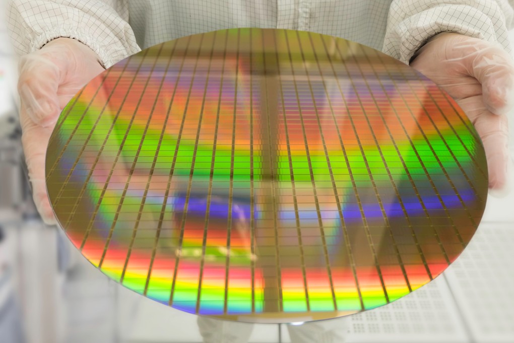 Hands holding a silicon wafers rainbow colours reflection light, working at clean room laboratory. Photo: Shutterstock