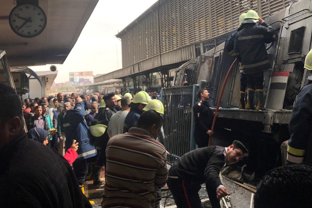 A member of security forces gestures as rescue workers and people gather at the scene after a fire caused deaths and injuries at the main railway station in Cairo. Photo: Reuters