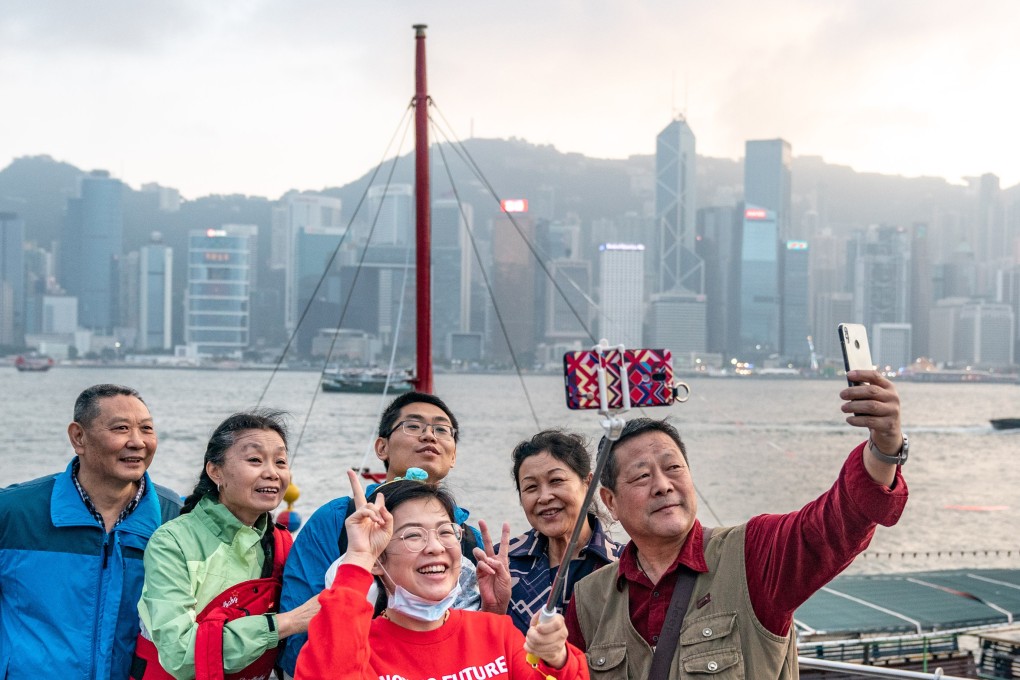 Mainland tourists take selfies in front of the Hong Kong city skyline. Chinese tourism numbers, including international travel, have held up despite uncertainty regarding the broader economy. Photo: Bloomberg