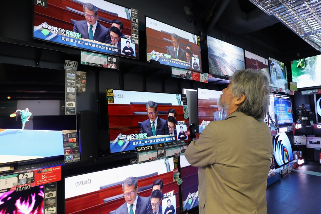 A man watches television screens as Financial Secretary Paul Chan Mo delivers his budget for 2019-20. Photo: Dickson Lee