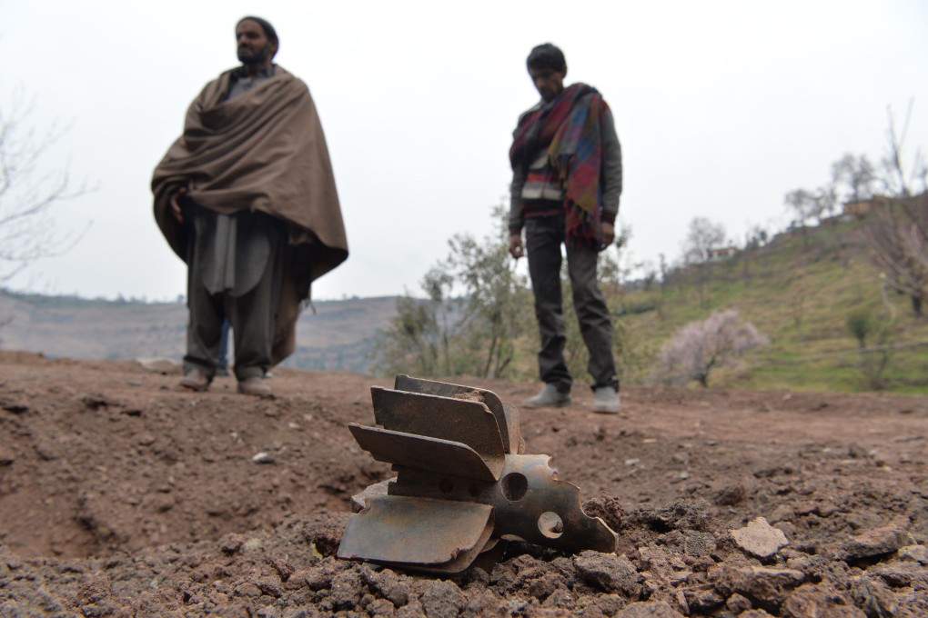 Men stand near the fin of an exploded mortar in India, near the line of control border with Pakistan. Photo: AFP
