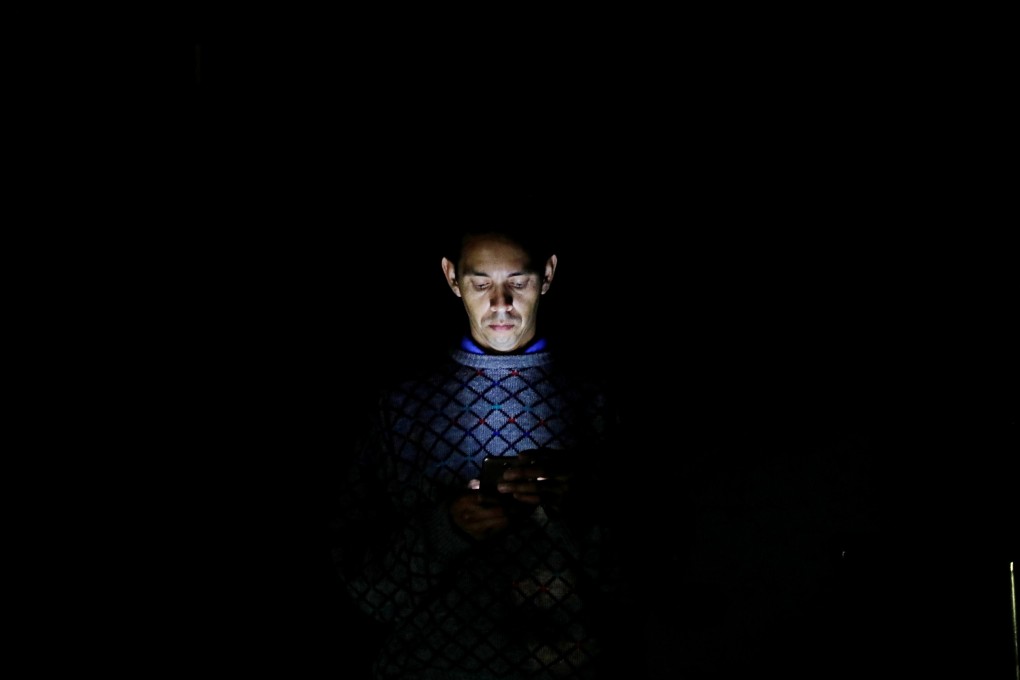 A man looks at his mobile phone during the blackout in Caracas, Venezuela. Photo: Reuters