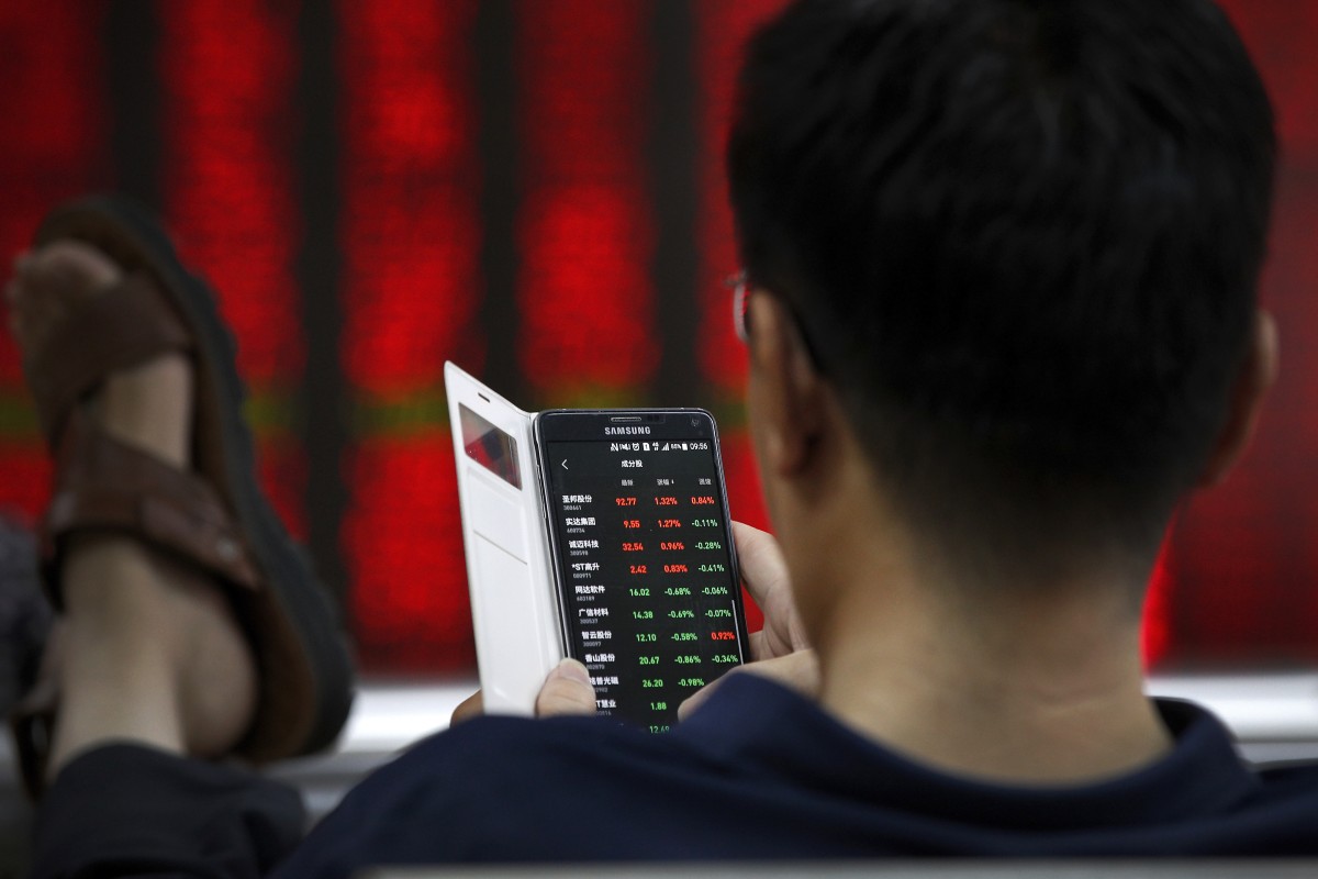 A man checks stock prices through his smartphone at a brokerage house in Beijing. Photo: AP Photo