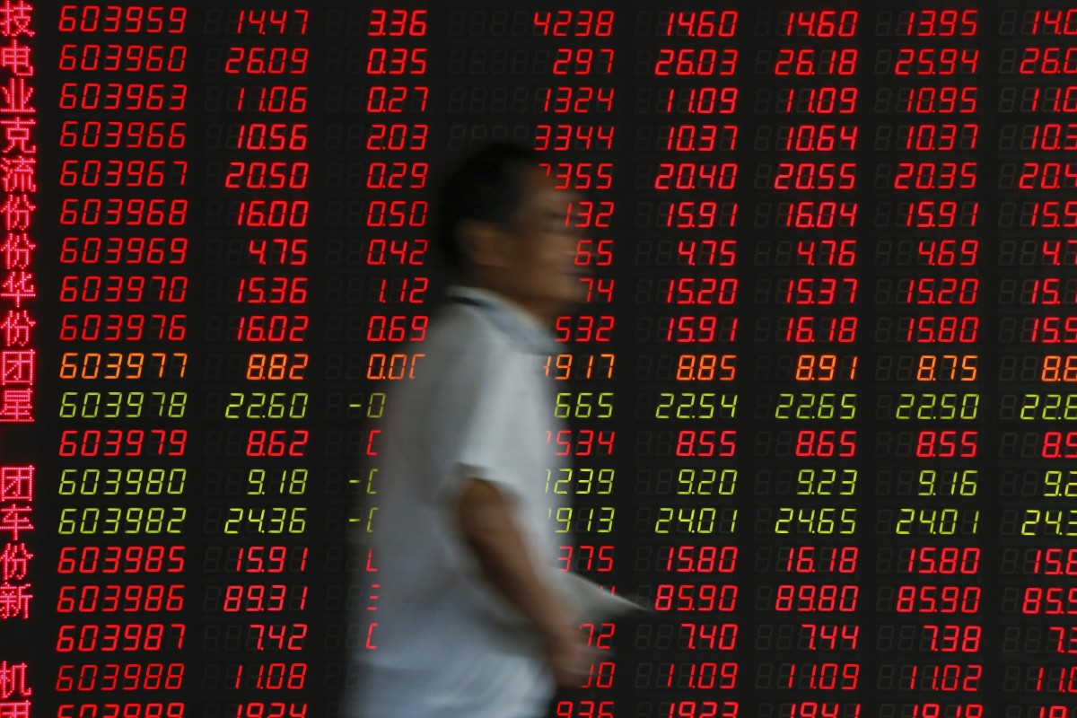An investor walks by an electronic board displaying stock prices at a brokerage in Beijing. Photo: AP Photo