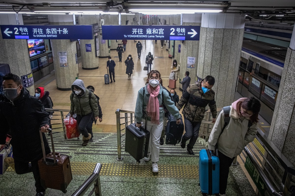 People wearing protective face masks with their luggage go up the steps in the subway station in Beijing on February 10, 2020. Photo: EPA-EFE