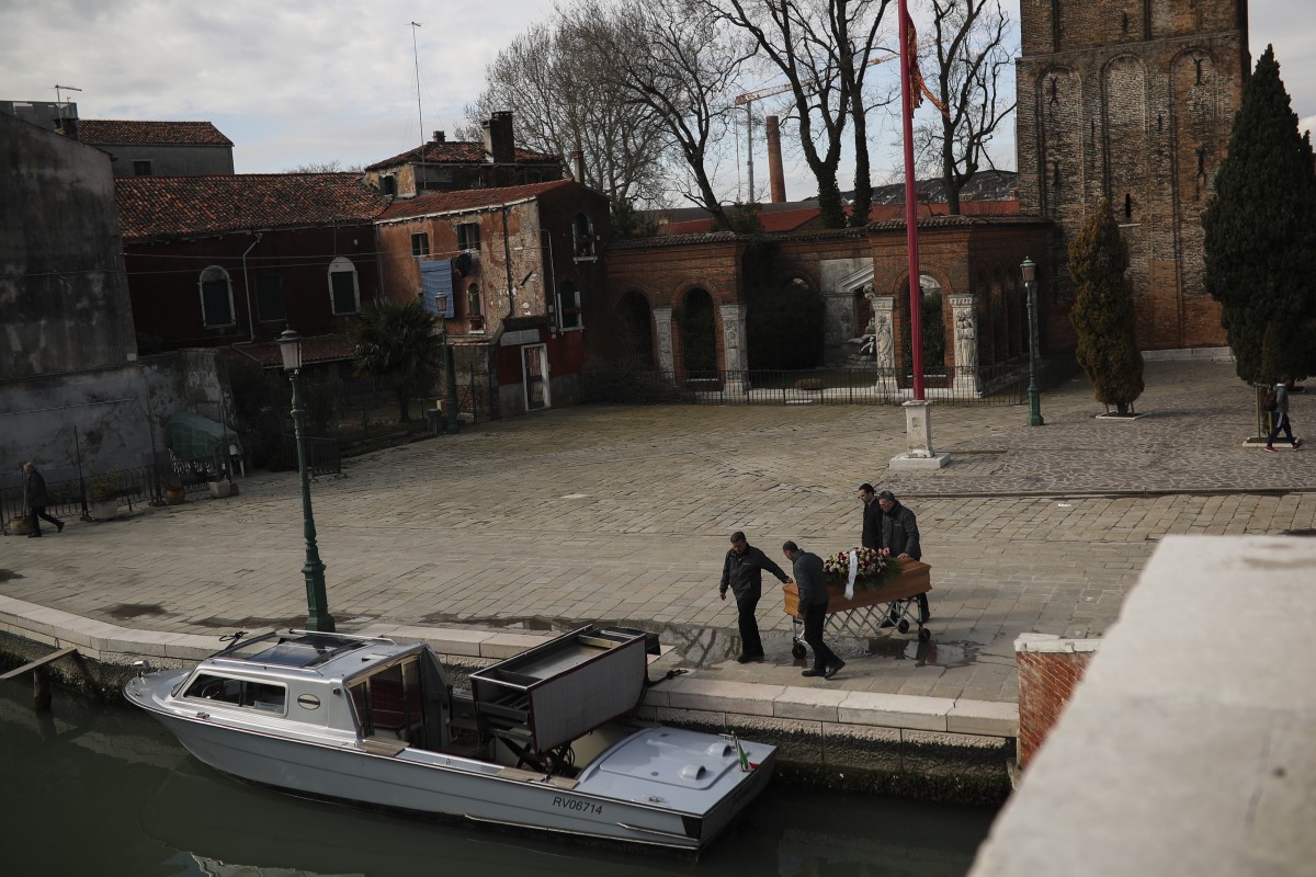 Funeral service workers push a coffin to place in a boat after a mass at the Murano island in Venice, Italy, on March 3, 2020. Photo: Associated Press