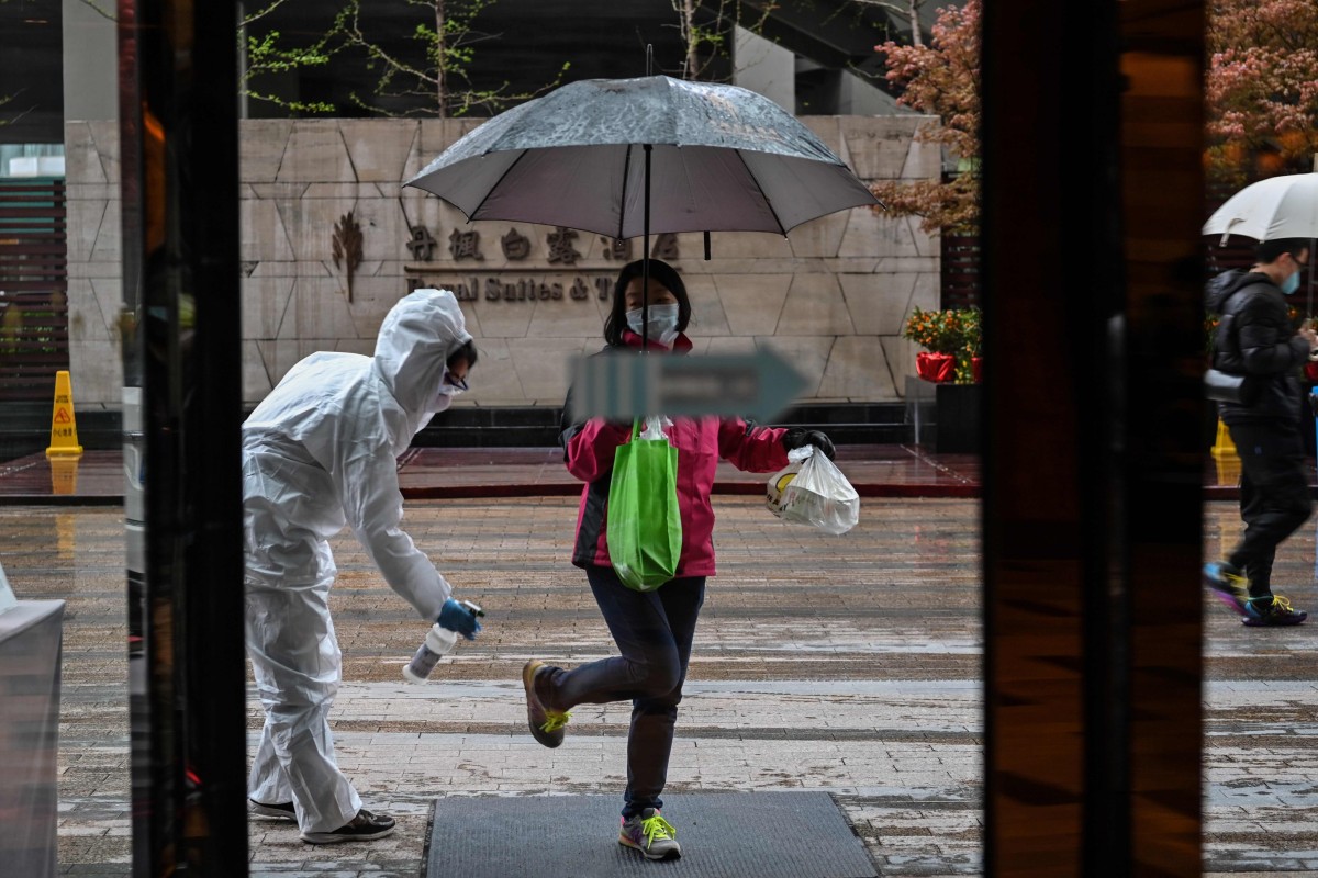 A hotel employee sprays disinfectant on an arriving guest, as a preventative measure against the COVID-19 coronavirus in Wuhan, China’s central Hubei province on March 29, 2020, a day after travel restrictions into the city were eased following the outbreak. Wuhan, the central Chinese city where the coronavirus first emerged last year, partly reopened on March 28 after more than two months of near total isolation for its population of 11 million. Photo: AFP