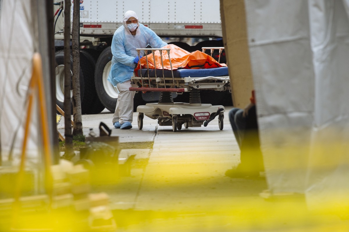 A medical worker in protective clothing moves the body of a deceased patient to a refrigerated overflow morgue outside the Wyckoff Heights Medical Center in Brooklyn, New York, U.S., on April 3, 2020. Photo: Bloomberg 