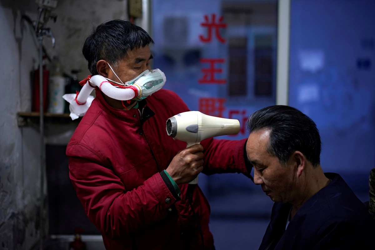 Barber Yang Guangyu wears his handmade mask assembled from a water bottle, mask and a plastic pipe, as he works after the lockdown was lifted in Wuhan, capital of Hubei province and China’s epicentre of the novel coronavirus disease. Photo: Reuters