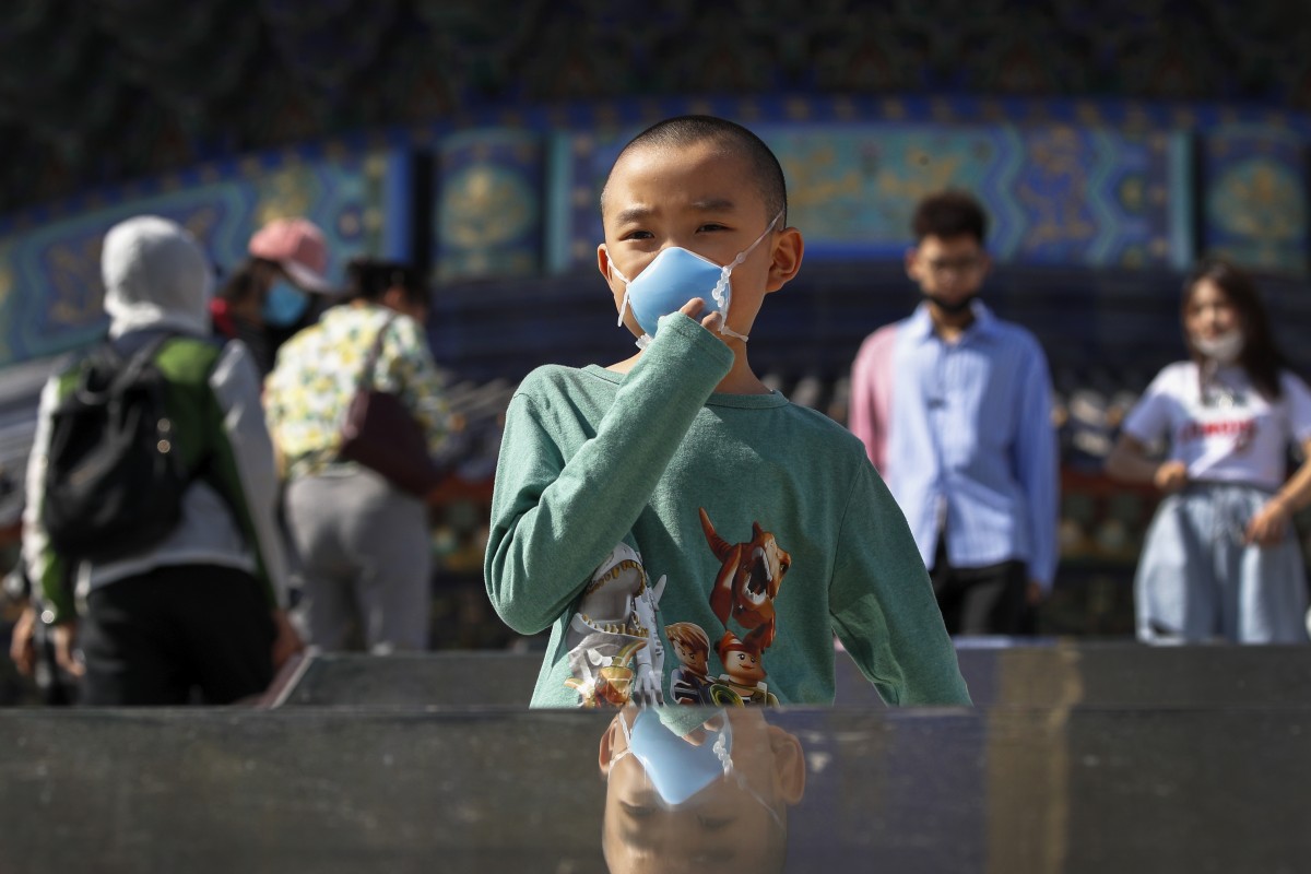 A child holds his protective face mask to help curb the spread of the new coronavirus as he visits to the capital's popular tourist spot of Temple of Heaven in Beijing on May 10, 2020. Photo: Associated Press
