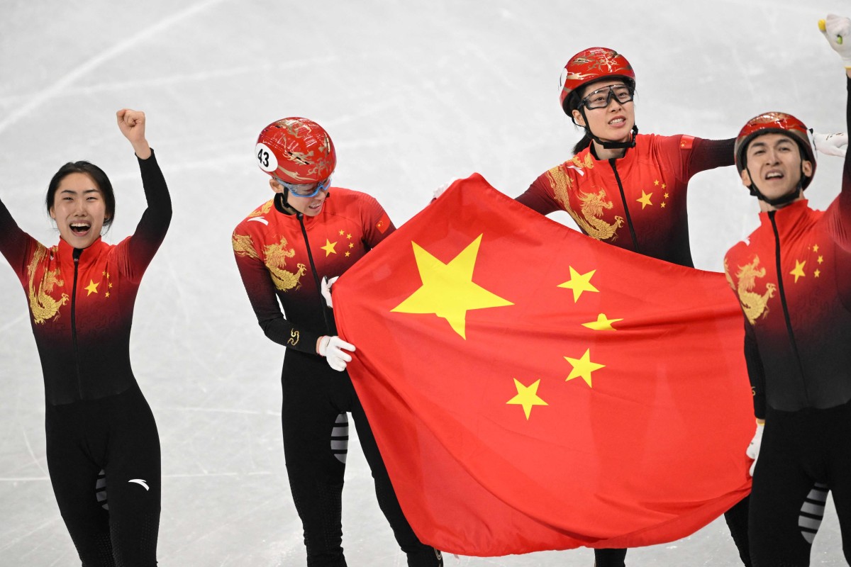 Chinese short track speed skaters celebrate with the national flag after winning mixed relay gold at the Beijing Winter Olympics. Photo: AFP
