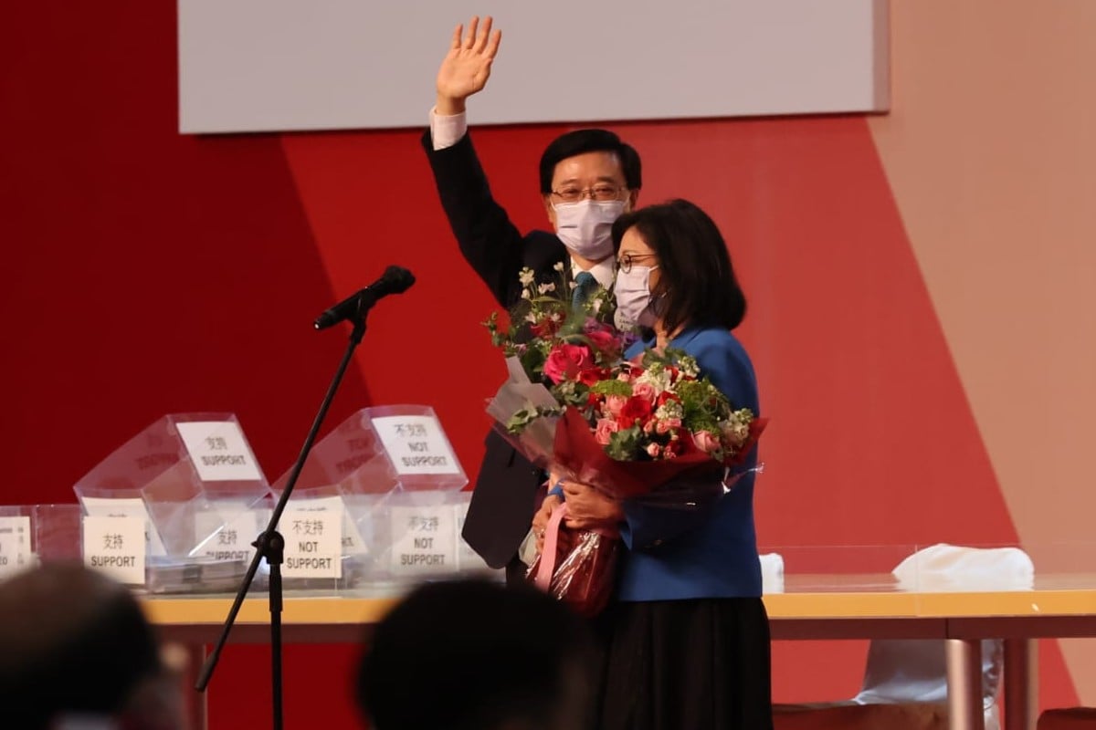 John Lee waves on stage, accompanied by his wife. Photo: Felix Wong