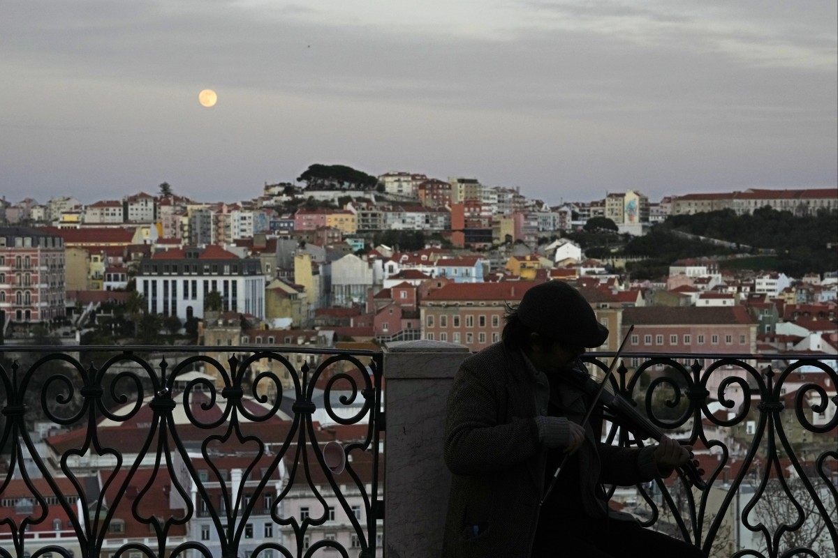 A young man plays the violin as night falls in Lisbon, the Portuguese capital. Photo: AP