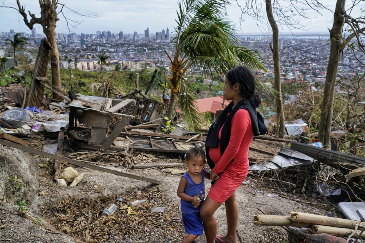A mother and son look at their house destroyed by Typhoon Rai. She has rice, four small cans of sardines and corned beef for Christmas. Photo: AP 