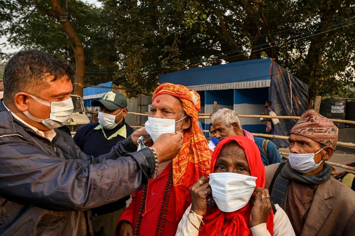 A police personnel distributes face masks to pilgrims in Kolkata. Photo: AFP