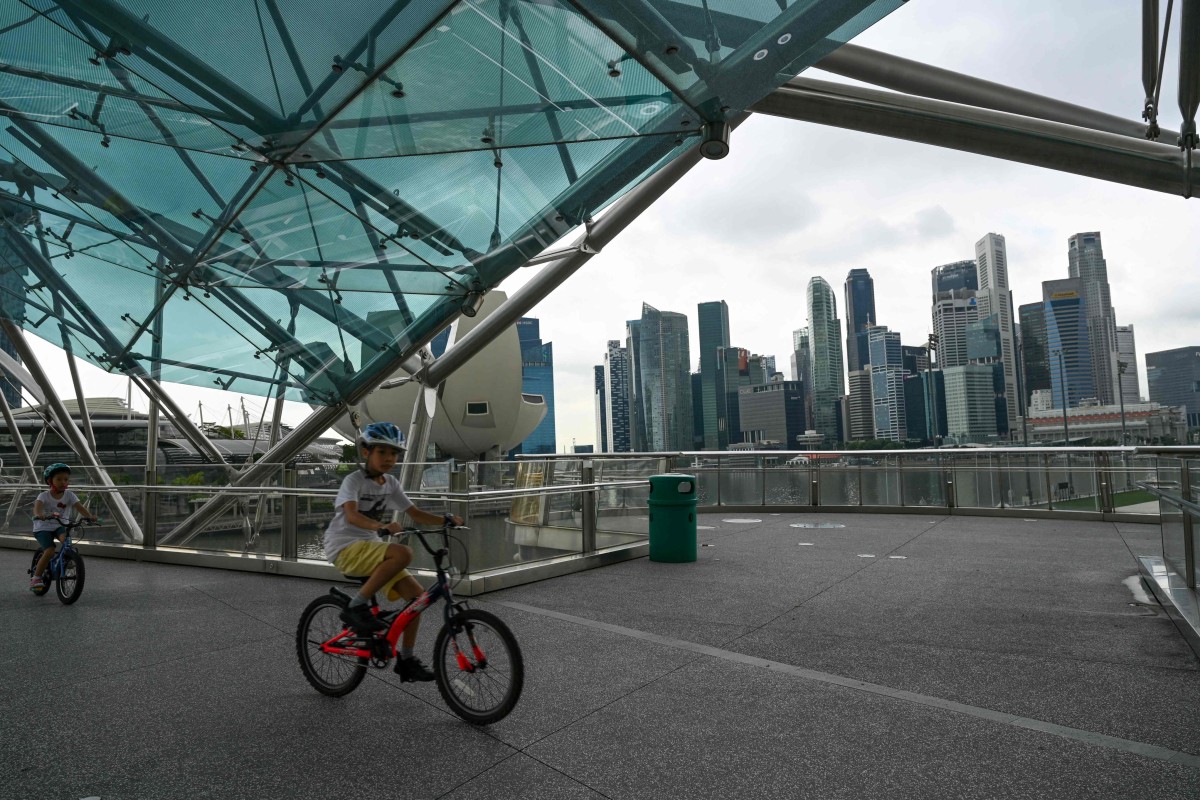 Children ride bikes along the Helix Bridge with a view of the financial business district in Singapore. Photo: AFP