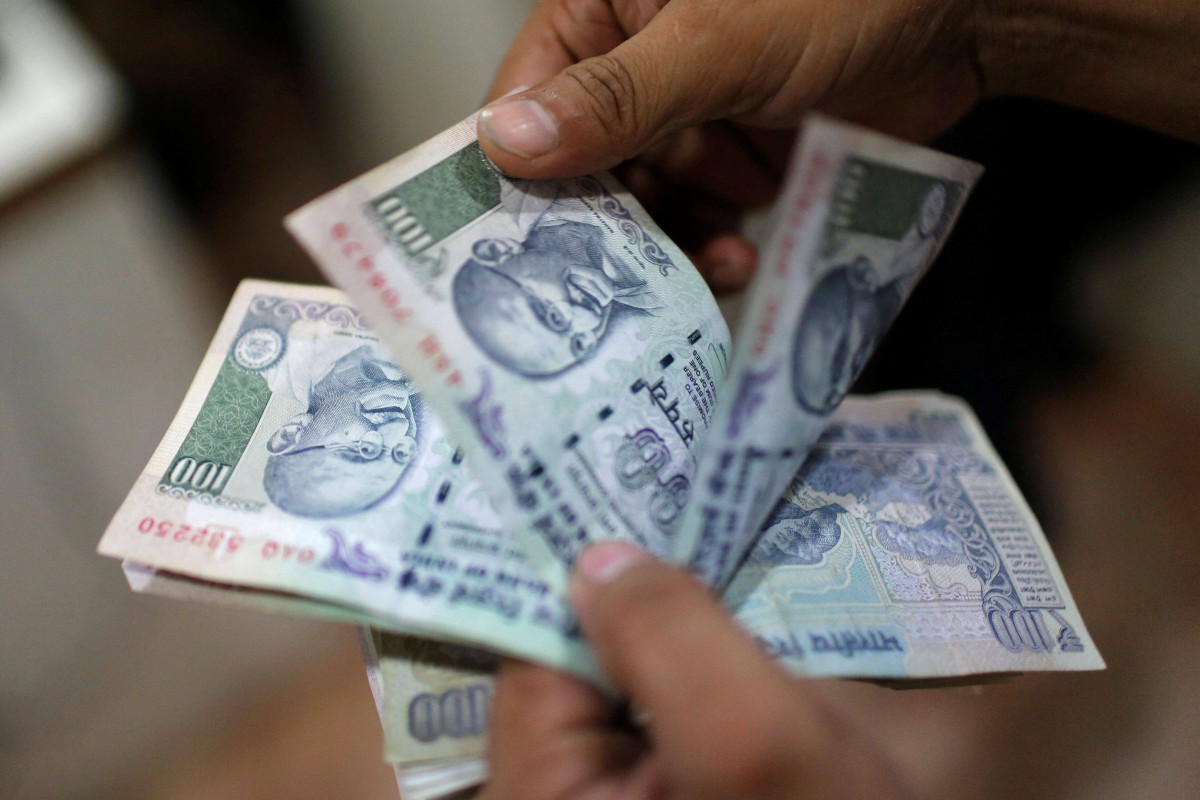 A man counts Indian rupee notes inside a private money exchange office in New Delhi. Photo: Reuters