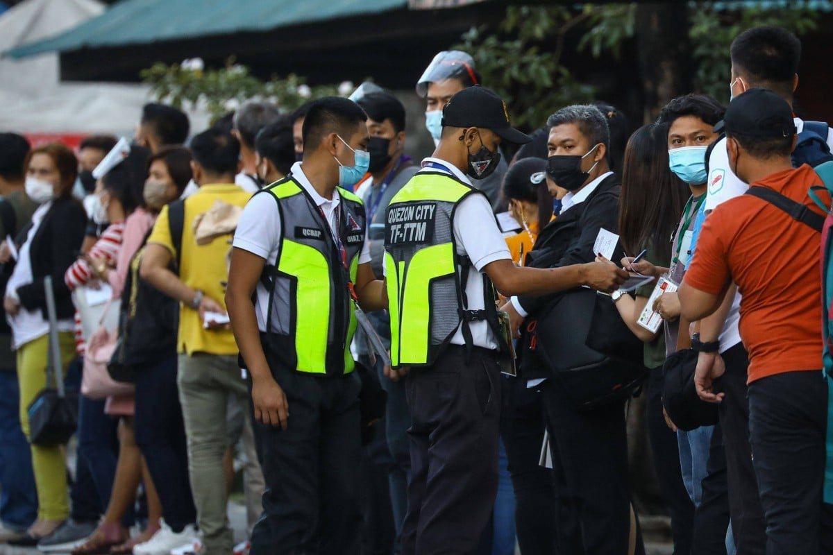 Transport authority personnel check Covid-19 vaccination cards of people queueing up at a bus station in Quezon City, suburban Manila on Tuesday. The government has banned unvaccinated people from using public transport amid a record surge in coronavirus cases. Photo: AFP