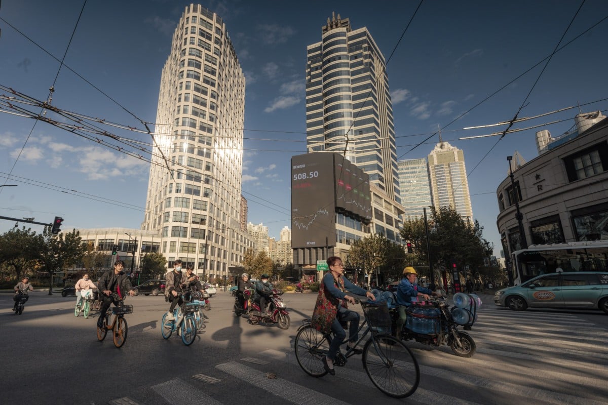 Cyclists seen on the street next to the large screen showing stock exchange data in Shanghai in November 2021. Photo:  EPA-EFE