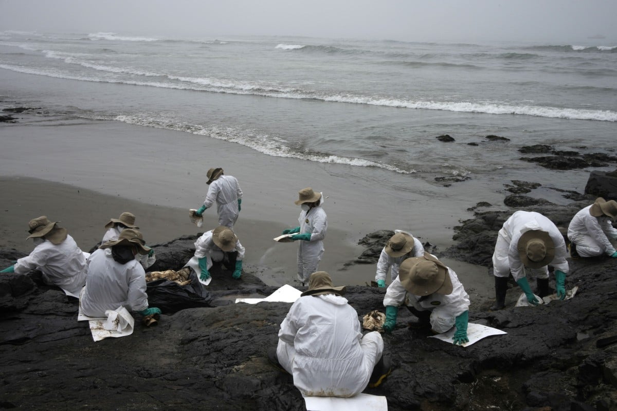 Workers clean oil on Cavero Beach in the Ventanilla district of Callao, Peru on January 22. Photo: AP 