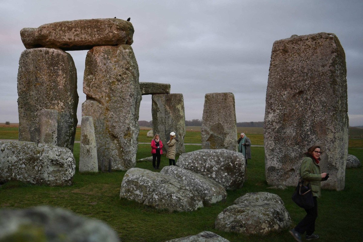 People visit the prehistoric monument Stonehenge near Amesbury in southern England on January 19, 2022. - As the sun rose over the frost on Salisbury Plain, Sarah Greaney summoned the prehistoric ghosts of the hundreds of workers who built Stonehenge. “These people are farmers, they have crops, they have animals and the turning of the year would have been a major part of their lifestyles,” Greaney, senior properties historian at English Heritage, told AFP. It is 4,500 years since labourers from across Britain and the European mainland descended on the vast plain in southwest England, hoisting the huge stones to form the now world-famous landmark. (Photo by Daniel LEAL / AFP) / TO GO WITH AFP STORY BY Anna CUENCA