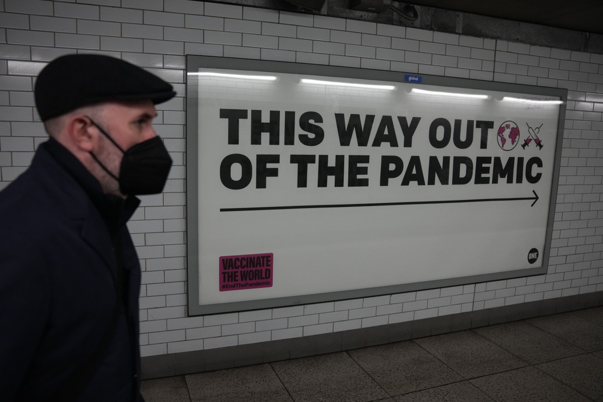 A man wearing a face mask walks past a health campaign poster in an underpass leading to Westminster underground train station in London in January. Photo: AP