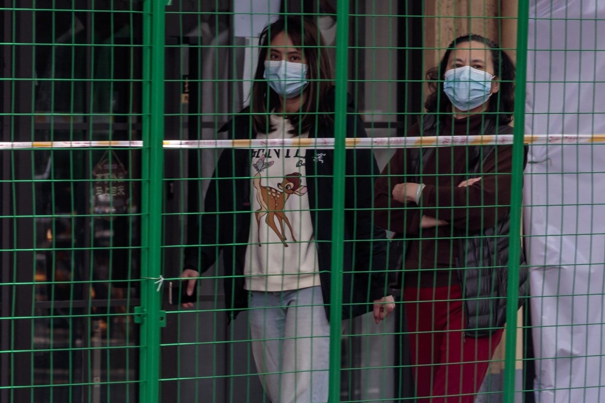 People walk next to the fence installed to block out a quarantined area in Shanghai. Photo: EPA-EFE