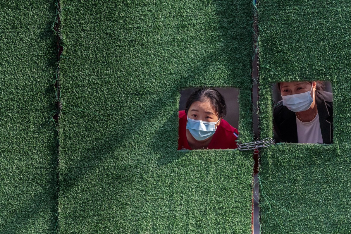 Women in quarantine look through a window cut into a gate amid Shanghai’s Covid-19 lockdown on May 1. Photo: EPA-EFE