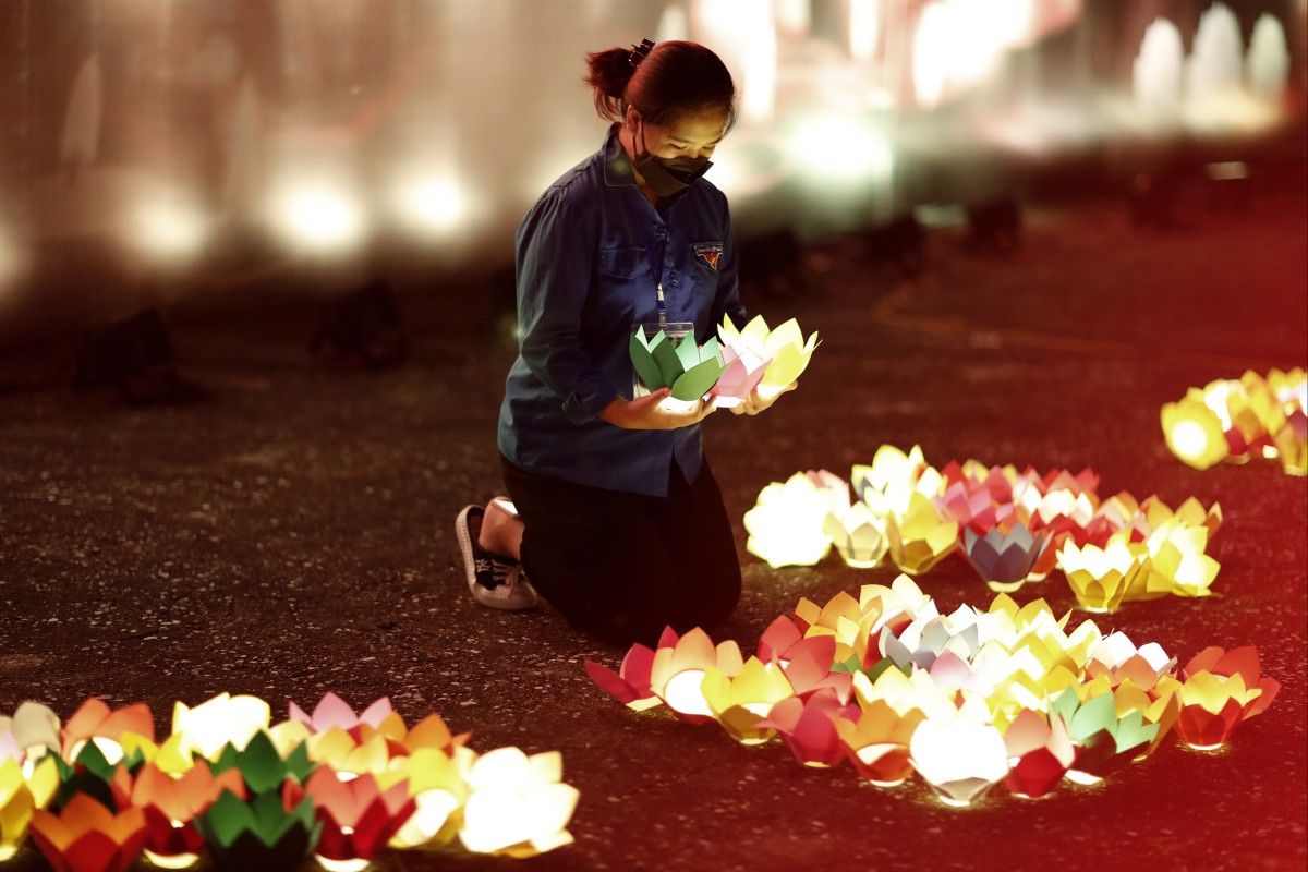 A girl places paper lights at a memorial for victims of the coronavirus pandemic, in Hanoi, Vietnam, on November 19, 2021. Photo: EPA-EFE