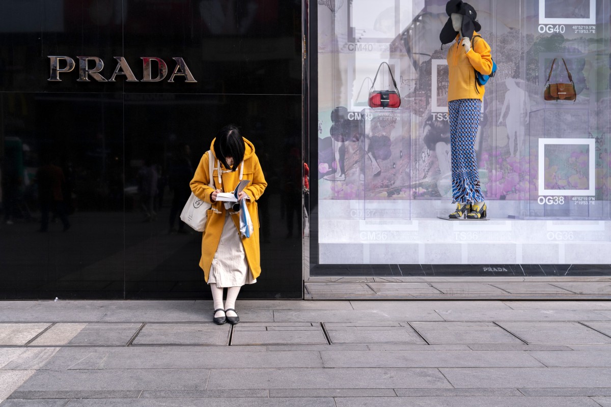 A woman reads a book outside a Prada store in Chengdu in March 2019. China is on course to be the world’s biggest luxury market by 2025. Photo: Shutterstock