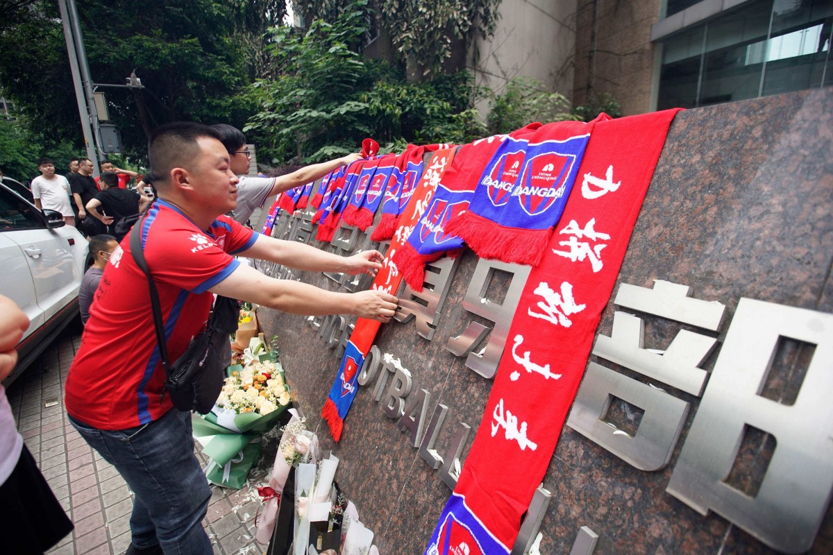 Fans of Chongqing Liangjiang Athletic place club merchandise and flowers outside its offices after it folded under heavy debts. Photo: AFP