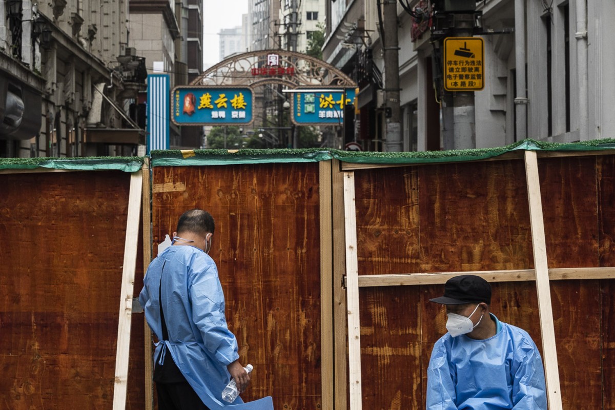 Security guards in personal protective equipment sit behind barriers surrounding a neighborhood placed under lockdown in Shanghai on May 30. Photo: Bloomberg