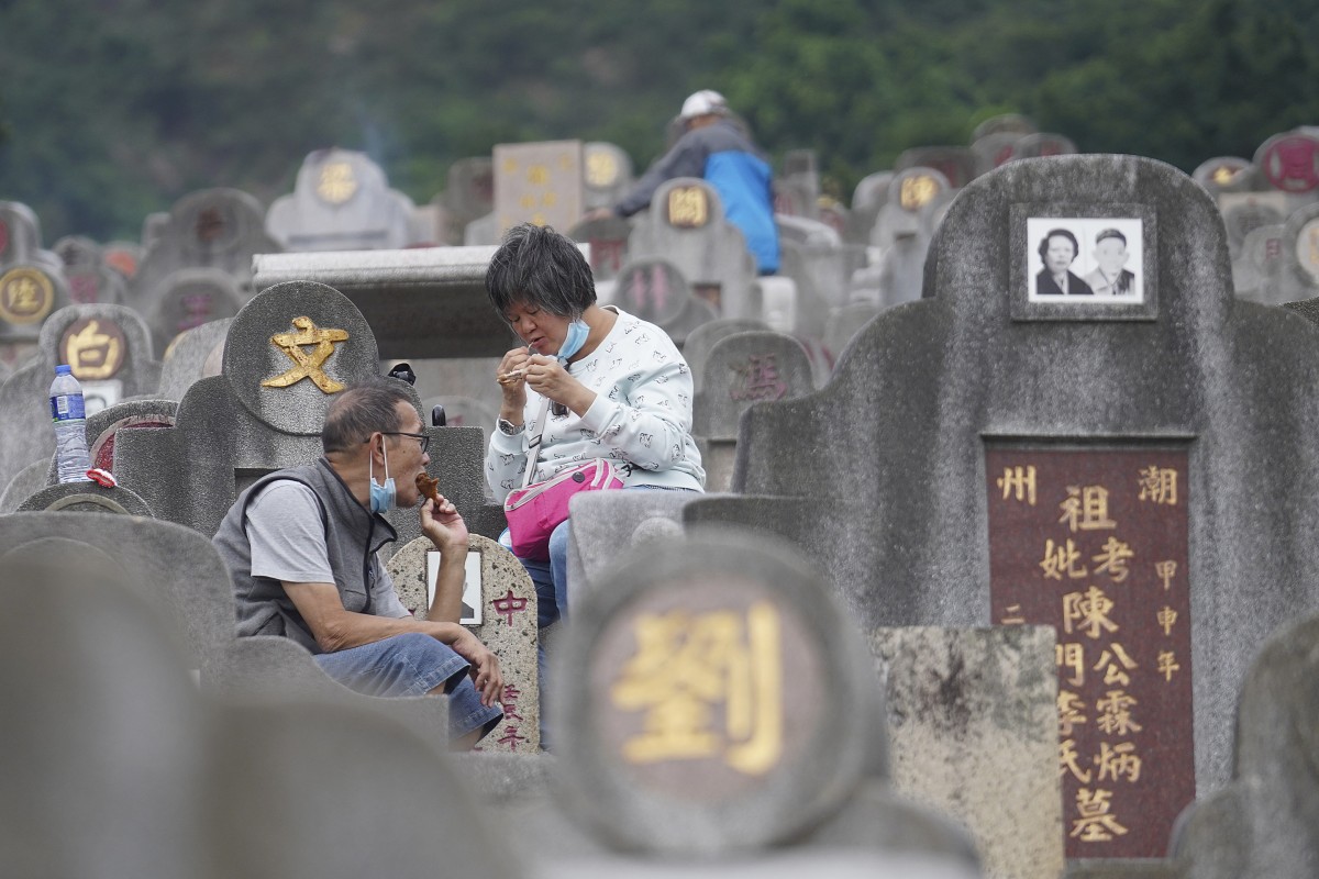 A couple eat a snack in between sweeping graves and burning offerings to pay homage to their ancestors in Diamond Hill Cemetery, Diamond Hill, Hong Kong. Photo: Winson Wong