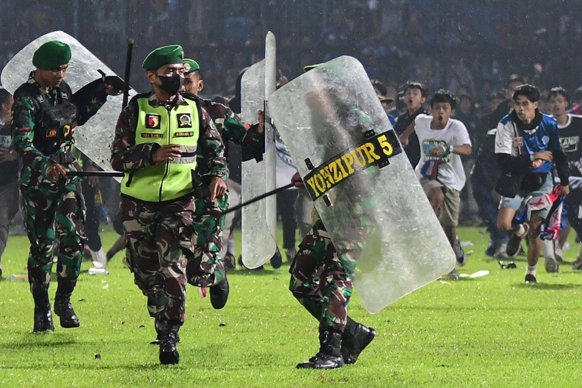 Arema supporters running on the pitch towards Indonesian army personnel after a football match in Malang. Photo: AFP 