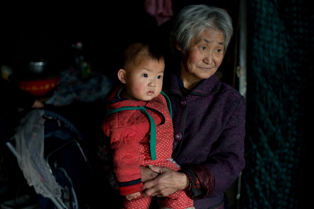 This photo taken on March 21, 2013 shows a woman with one of her grandchildren in their home in Chengde, Hebei province. Photo: AFP 