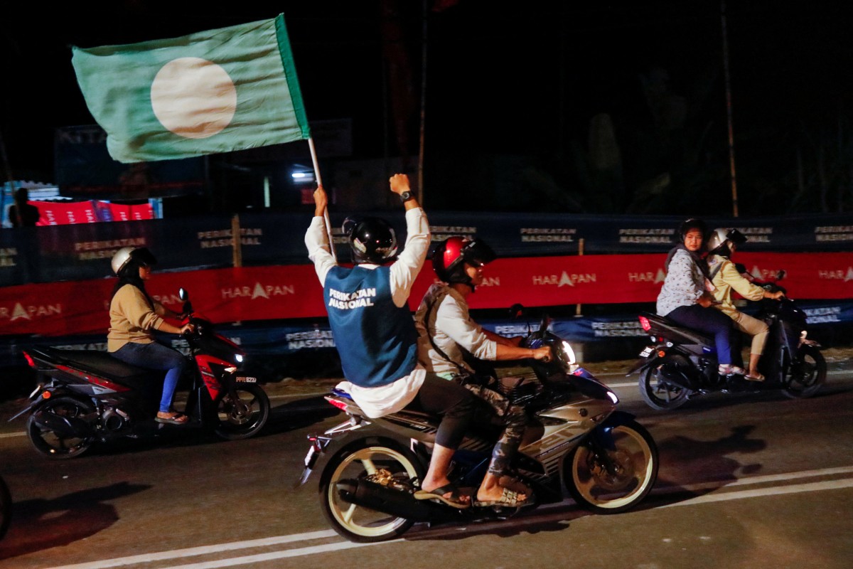 A pillion waves a PAS flag in Penang, Malaysia, on November 18, 2022. Photo: Reuters