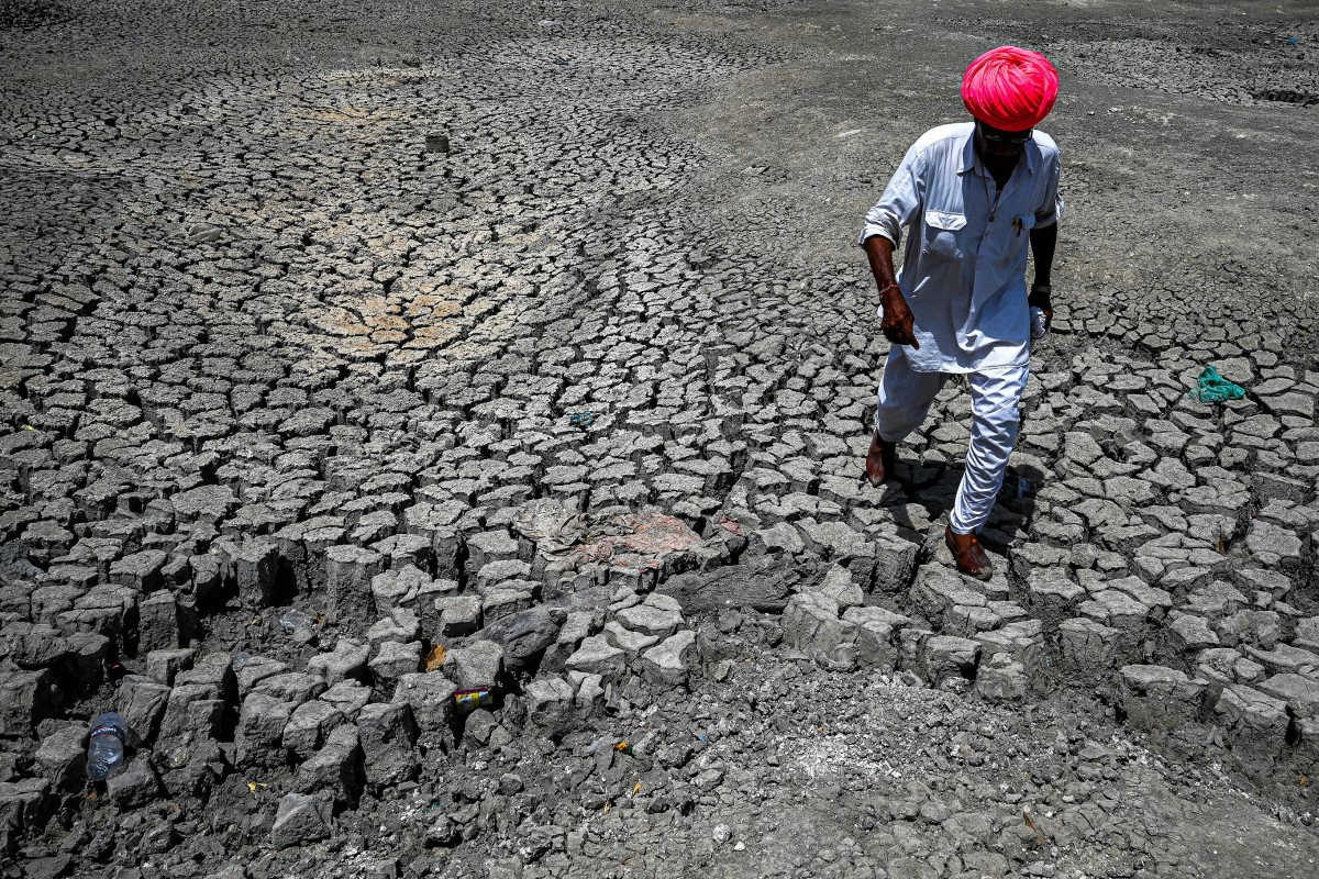 A villager walks through the cracked bottom of a dried-out pond on a hot summer day in India’s desert state of Rajasthan. Photo: AFP via Getty Images