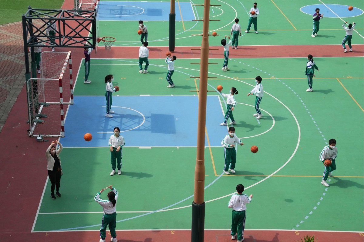 Schoolchildren play basketball at the height of the pandemic with masks on - but a survey has found many have kept wearing them because of worries about their looks. Photo: Sam Tsang