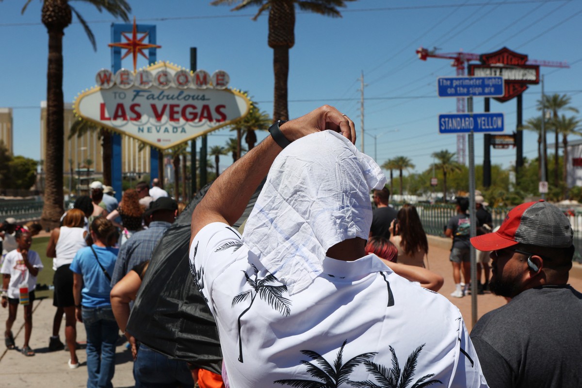 Satya Soviet Patnaik shields himself from the sun while waiting in line to take a photo at the historic Welcome to Las Vegas Sign during a heat wave in Las Vegas. Photo: AFP