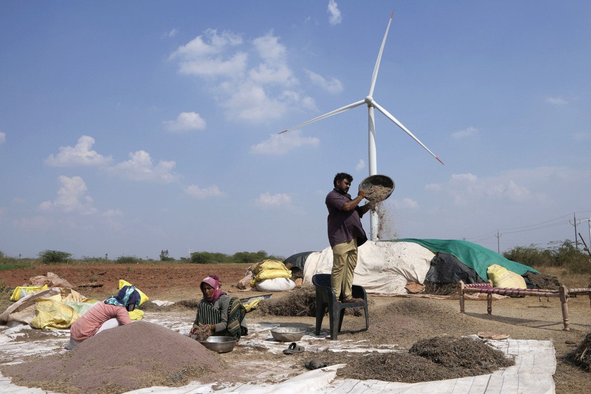 A family works in a field near a wind turbine in India. China and India have embarked on ambitious clean energy expansion projects. Photo: AP