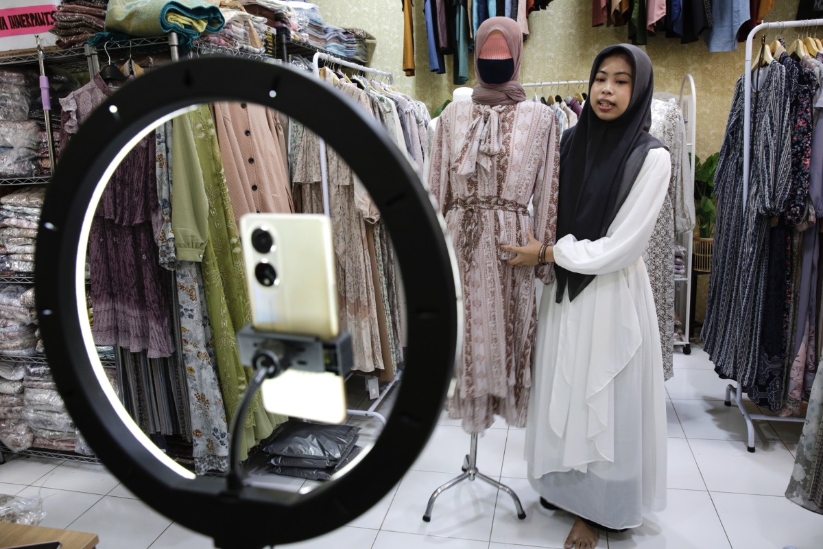 A sales woman showcases a dress as she live-streams on an e-commerce platform at a shop in Depok, Indonesia. President Joko Widodo’s administration has outlawed commercial transactions on all social media platforms. Photo: EPA-EFE