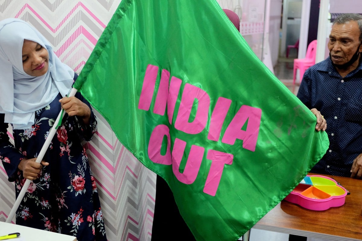 A worker with Mohamed Muizzu’s Progressive Party of Maldives poses with an “India Out” flag in Male last year. Photo: Reuters
