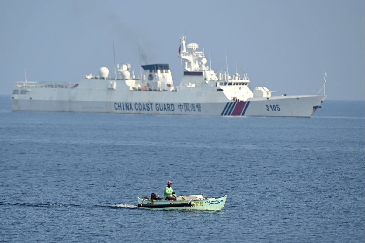 A Philippine fisherman aboard his wooden boat sail past a Chinese coast guard ship near the Chinese-controlled Scarborough Shoal in disputed waters of the South China Sea. Photo: AFP