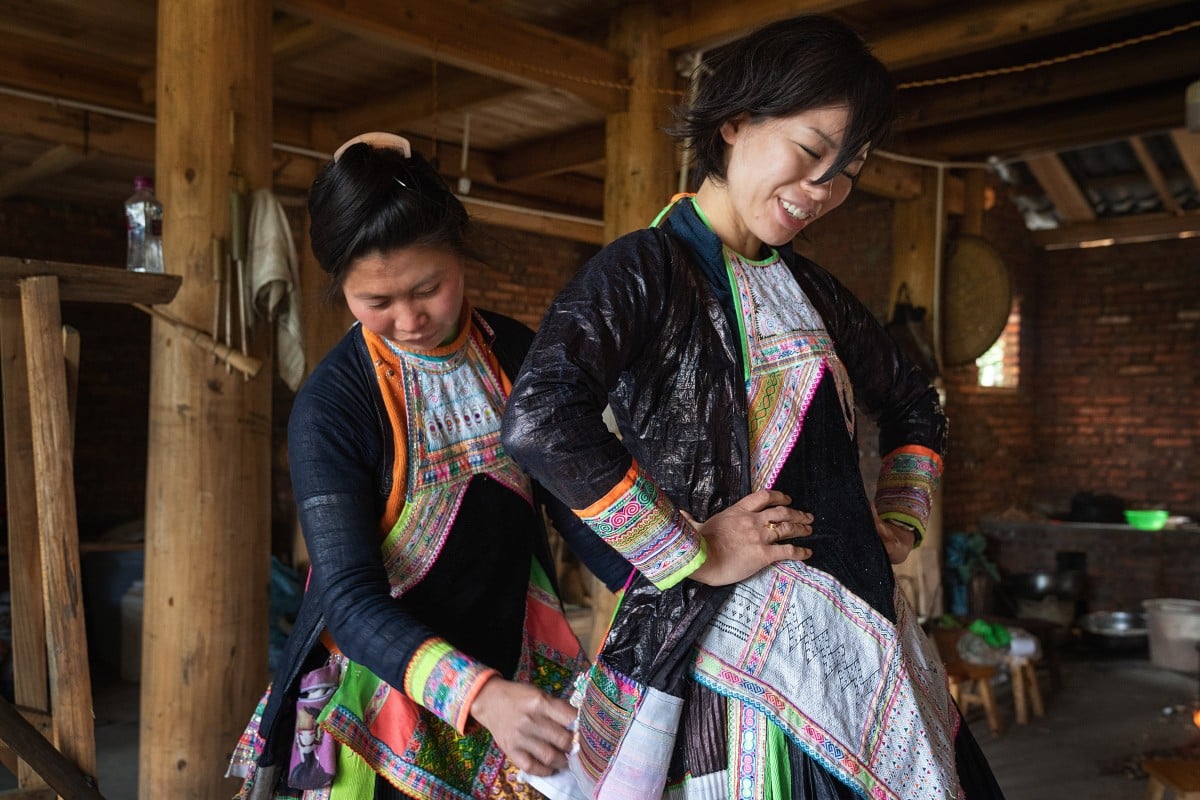 Hand-weaver Fei Fei (left) dresses American luxury fashion designer Angel Chang in one of her handmade outfits in Guizhou, China. Photo: Justin Jin