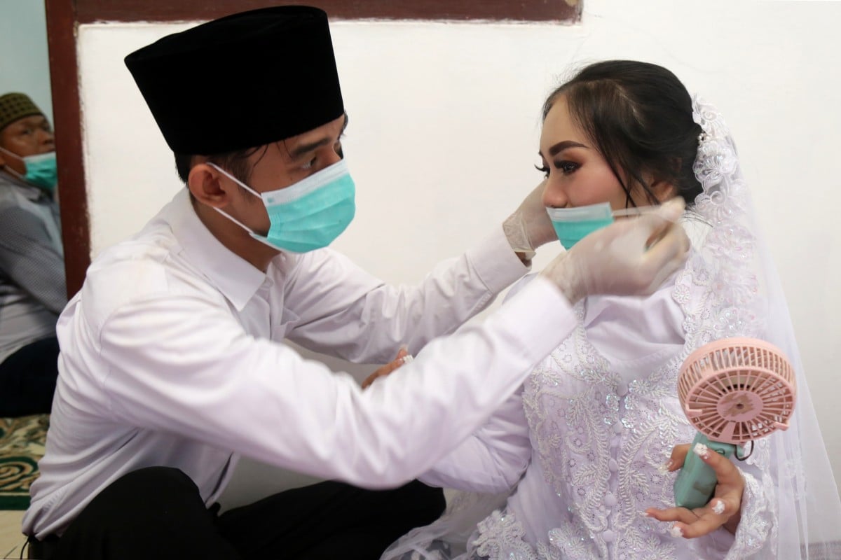 A groom puts a face mask on his bride before their wedding ceremony in Jakarta. Indonesia recorded only 1.79 million marriages in 2020. Photo: AFP 