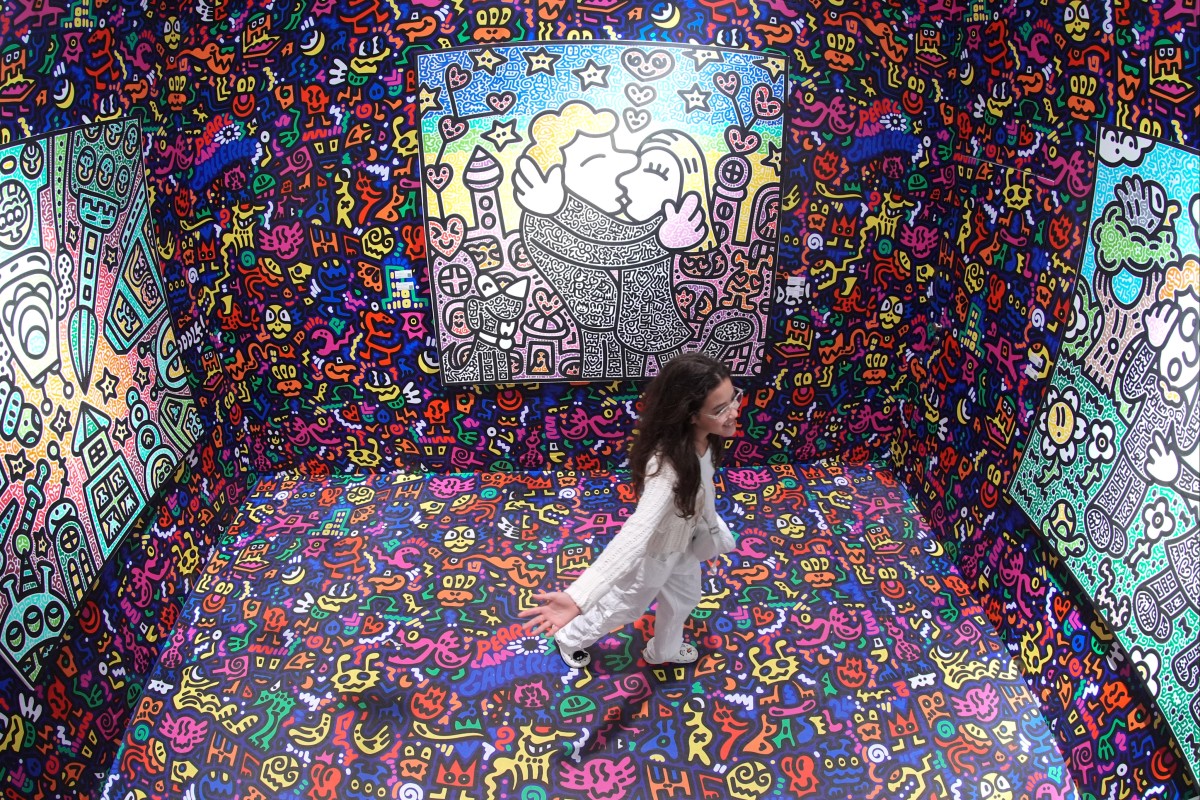 A visitor poses for a photo next to the artwork titled “Mas jumps in his Vortex to DoodleLand” by Mr Doodle. Photo: Eugene Lee